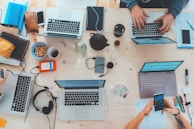 people sitting down near table with assorted laptop computers