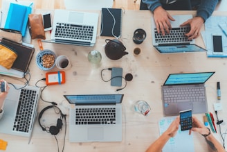 people sitting down near table with assorted laptop computers