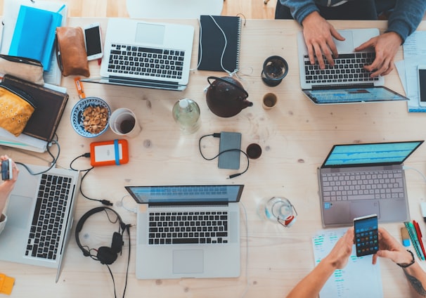 people sitting down near table with assorted laptop computers