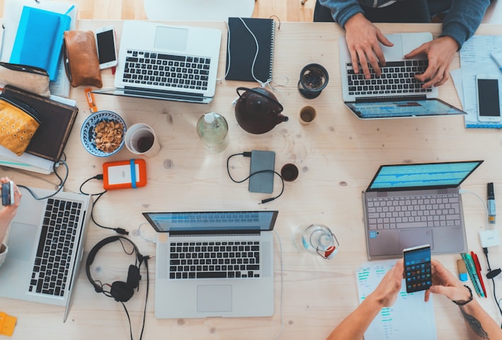 people sitting down near table with assorted laptop computers