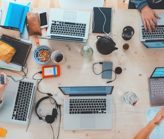 people sitting down near table with assorted laptop computers