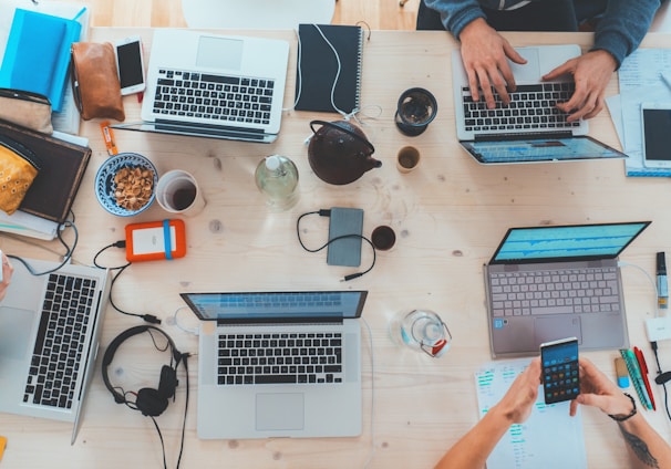 people sitting down near table with assorted laptop computers