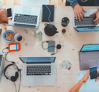 people sitting down near table with assorted laptop computers