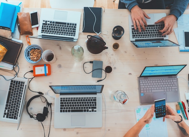 people sitting down near table with assorted laptop computers