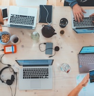 people sitting down near table with assorted laptop computers