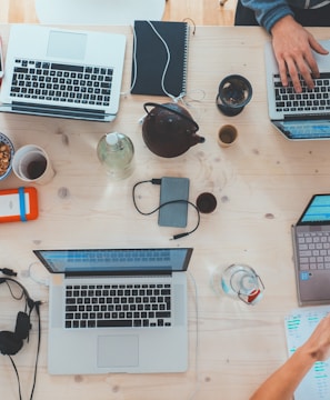 people sitting down near table with assorted laptop computers