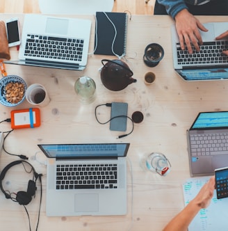 people sitting down near table with assorted laptop computers