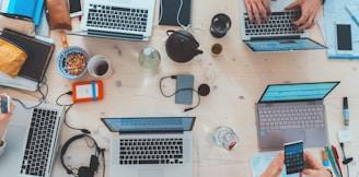 people sitting down near table with assorted laptop computers