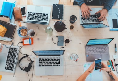 people sitting down near table with assorted laptop computers