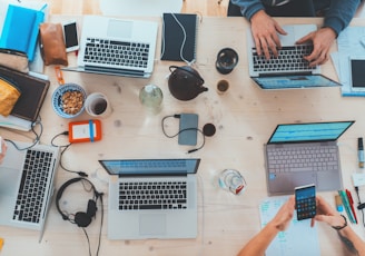 people sitting down near table with assorted laptop computers