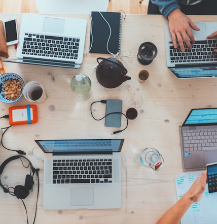 people sitting down near table with assorted laptop computers