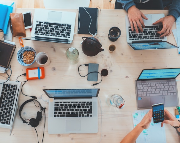 people sitting down near table with assorted laptop computers