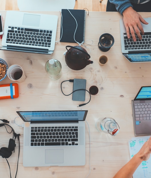 people sitting down near table with assorted laptop computers