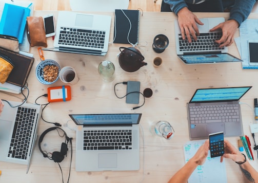 people sitting down near table with assorted laptop computers