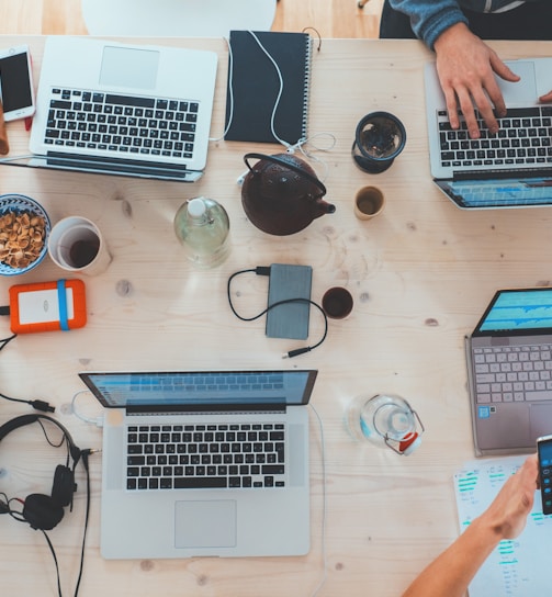 people sitting down near table with assorted laptop computers