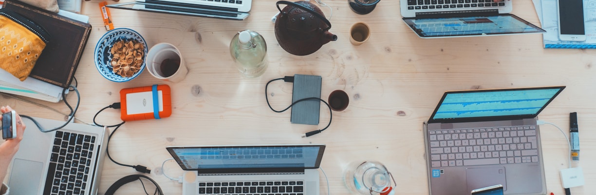 people sitting down near table with assorted laptop computers