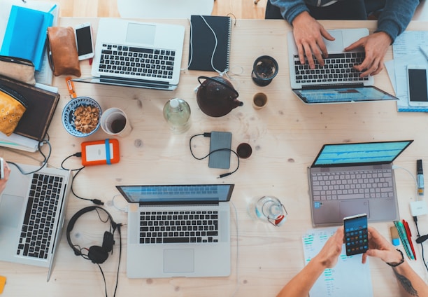 people sitting down near table with assorted laptop computers