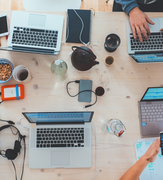 people sitting down near table with assorted laptop computers