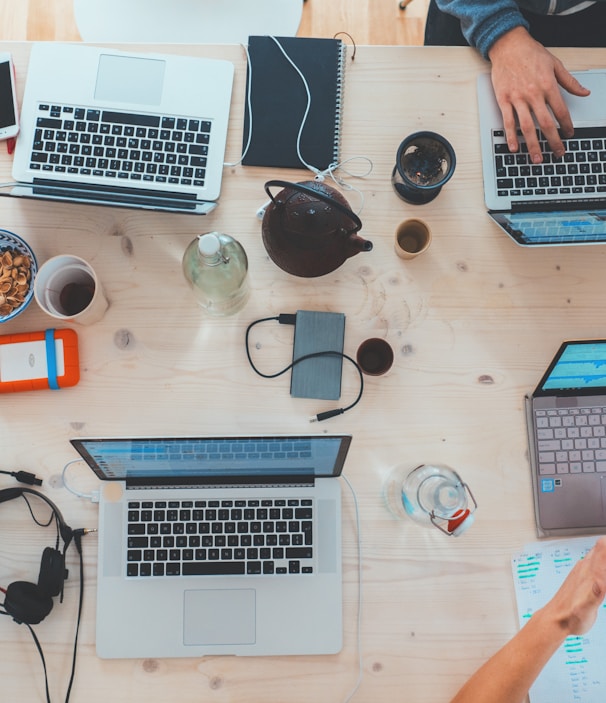 people sitting down near table with assorted laptop computers