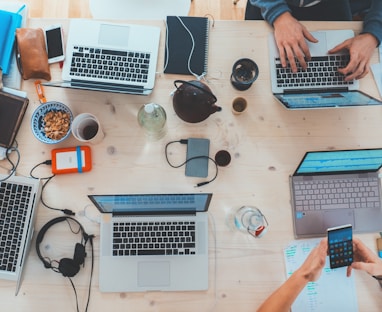 people sitting down near table with assorted laptop computers