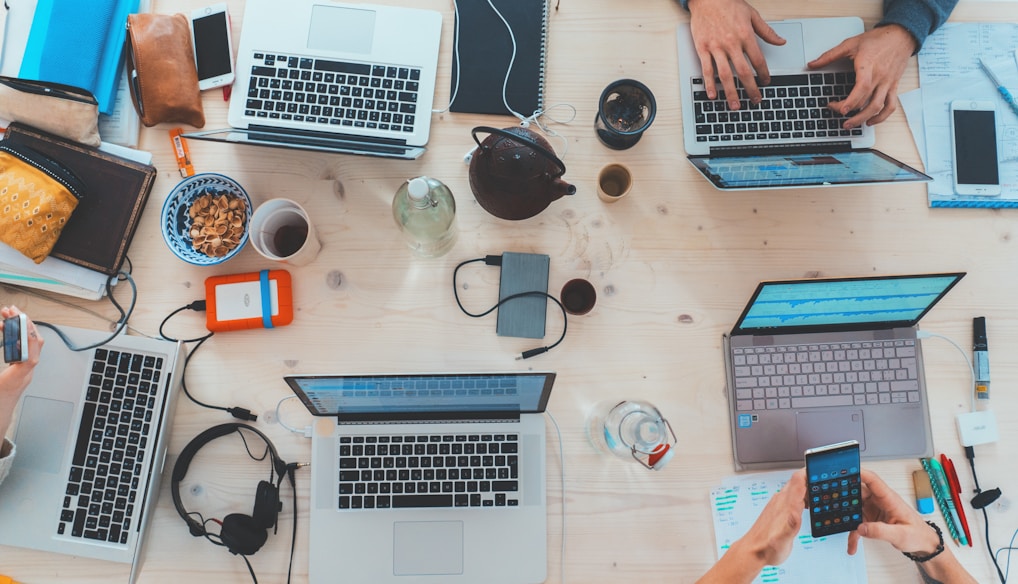 people sitting down near table with assorted laptop computers