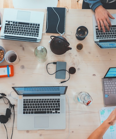 people sitting down near table with assorted laptop computers