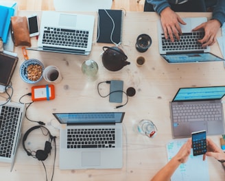 people sitting down near table with assorted laptop computers