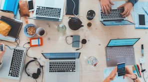 people sitting down near table with assorted laptop computers