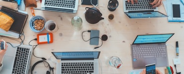 people sitting down near table with assorted laptop computers