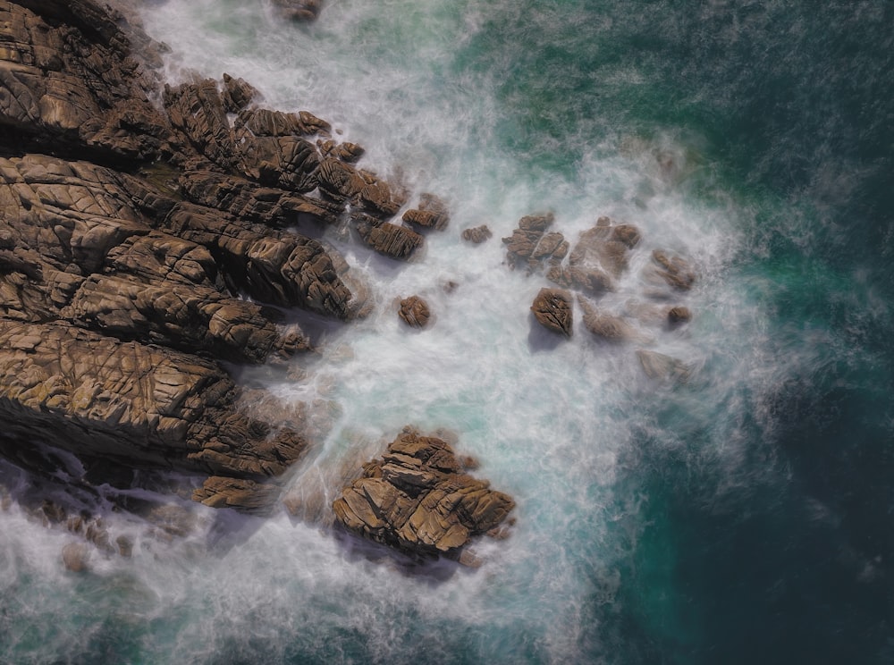 brown rock formation on sea aerial photography