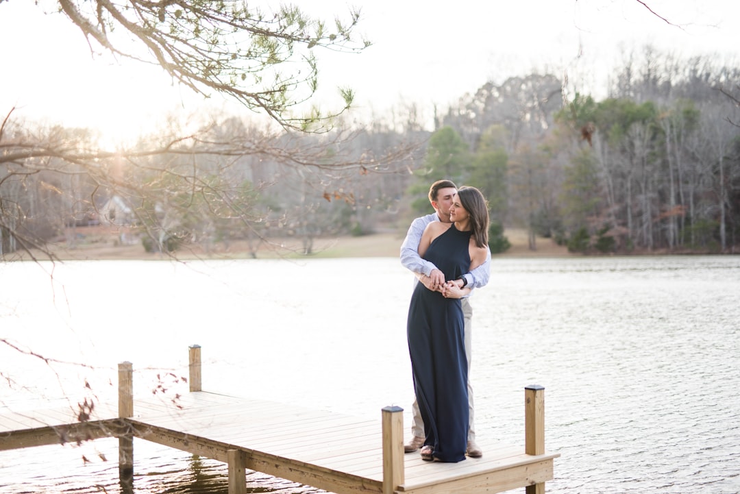 man and woman hugging on brown wooden dock during daytime