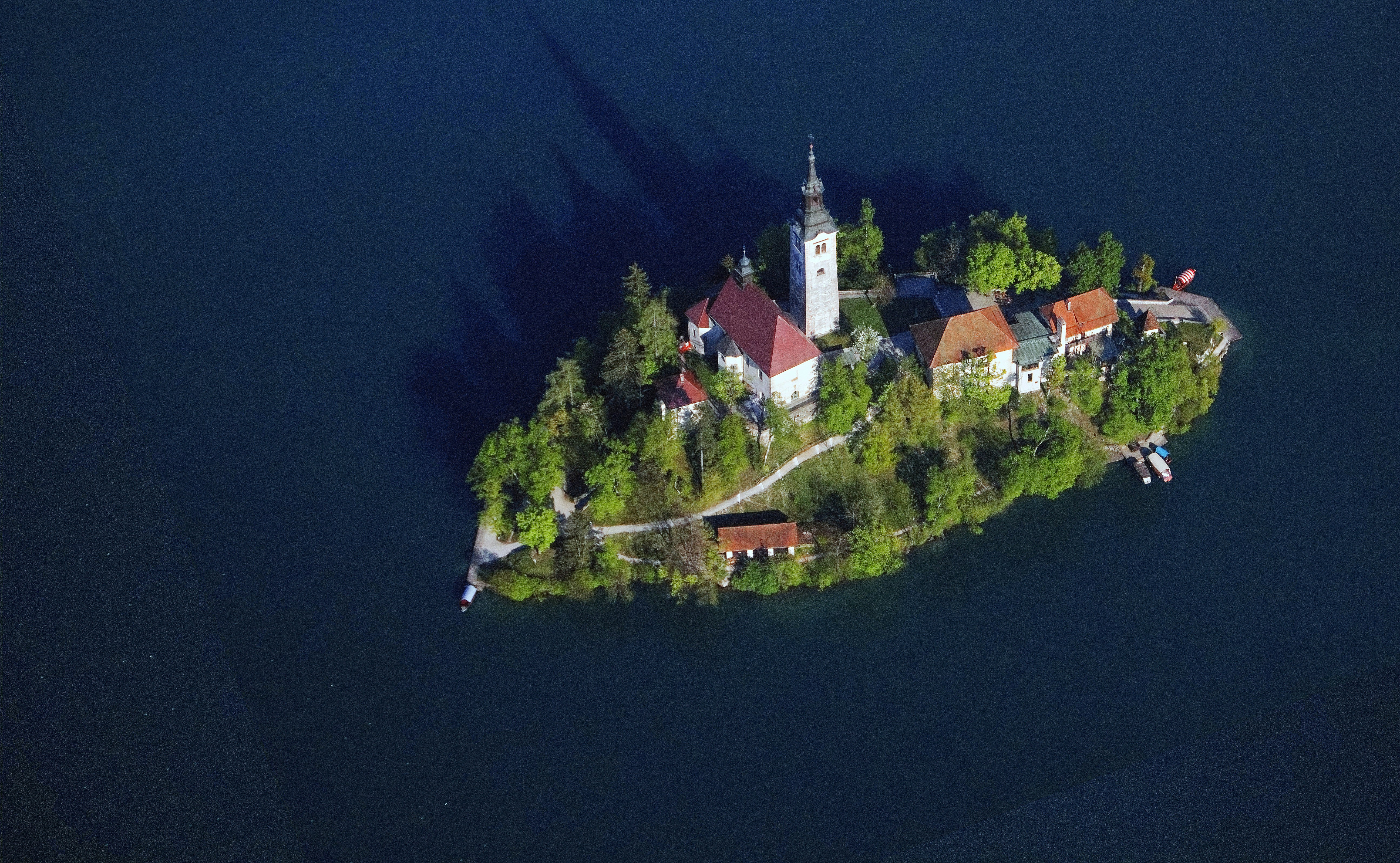 high-angle photo of white and red houses on small island, aerial shot of the island on lake Bled, Slovenia