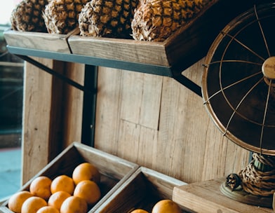 pineapple and orange fruits on brown wooden rack