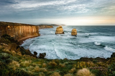 HDR photo of two rock formation on sea under cloudy sky during daytime
