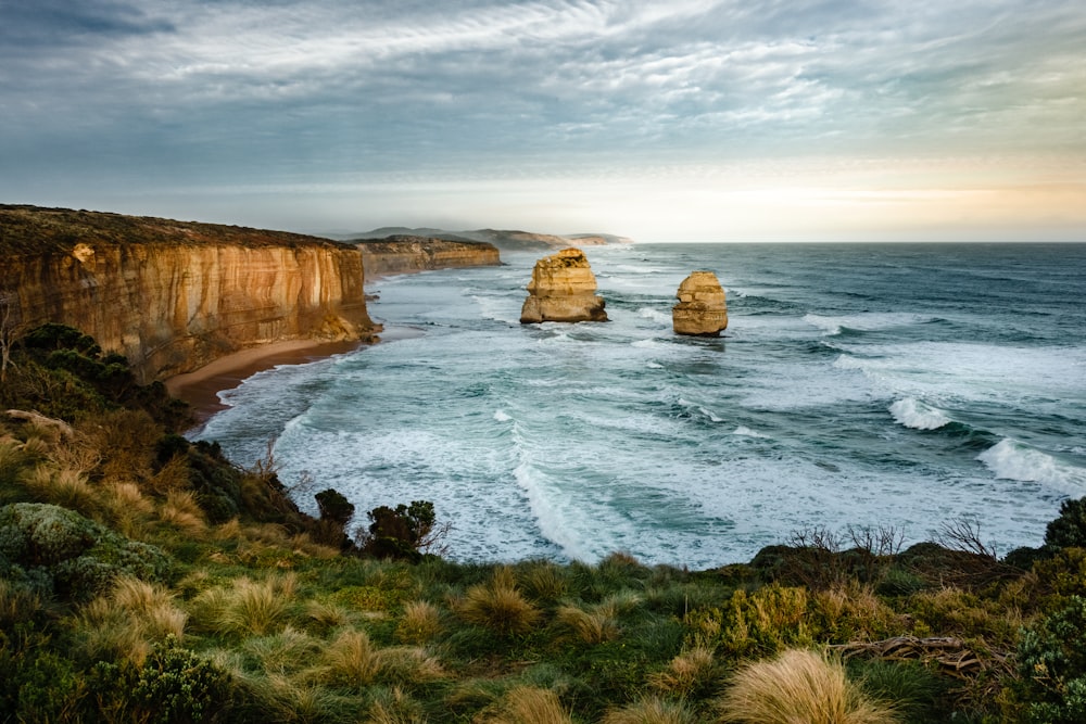 Foto HDR de duas formações rochosas no mar sob céu nublado durante o dia