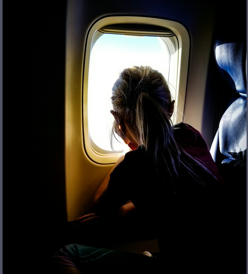 woman sitting on plane while looking at the window
