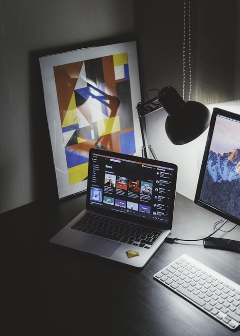 turned on MacBook on table beside iMac