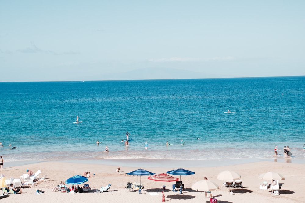 people on beach under patio umbrellas