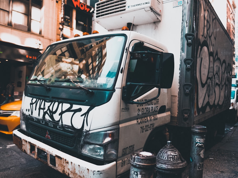 white and black Mitsubishi truck beside orange vehicle