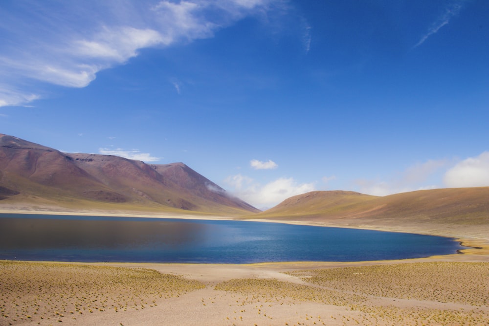 body of water surrounded by sand at daytime