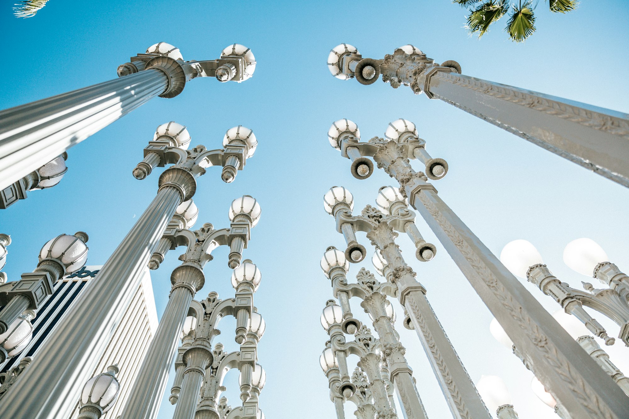 a group of decorative lamposts, viewed from below, against a bright sunny sky