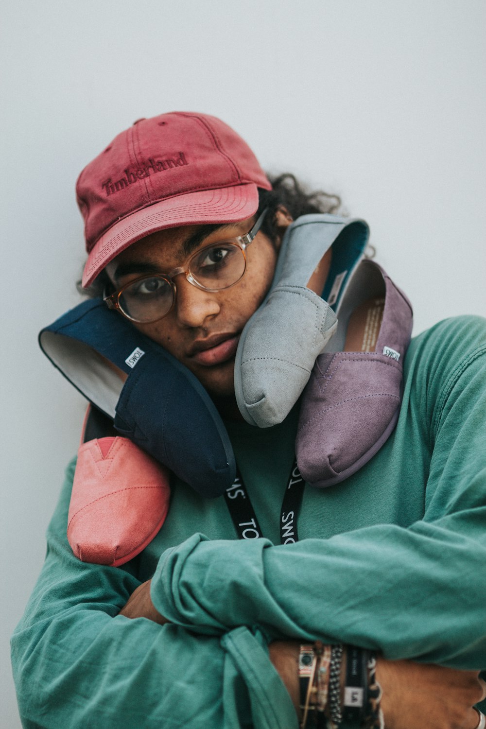 person with three assorted-color Toms shoes on his face