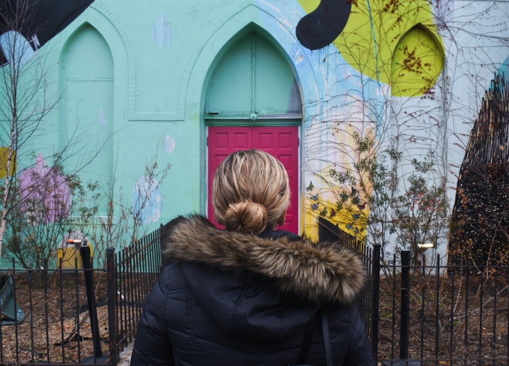 femme portant une veste parka debout devant la maison turquoise