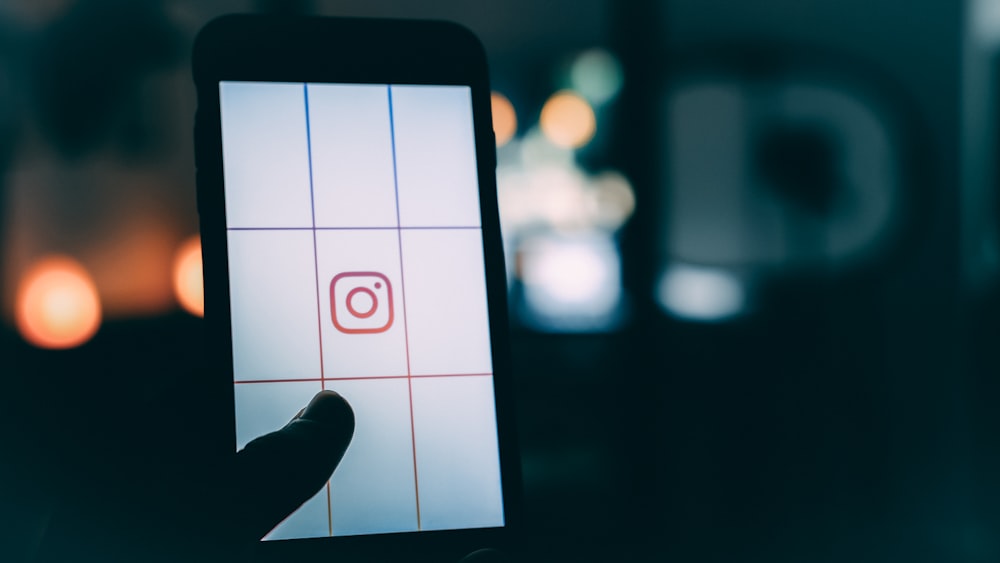 personne utilisant un smartphone avec une capture d’écran du logo Instagram bokeh photographie