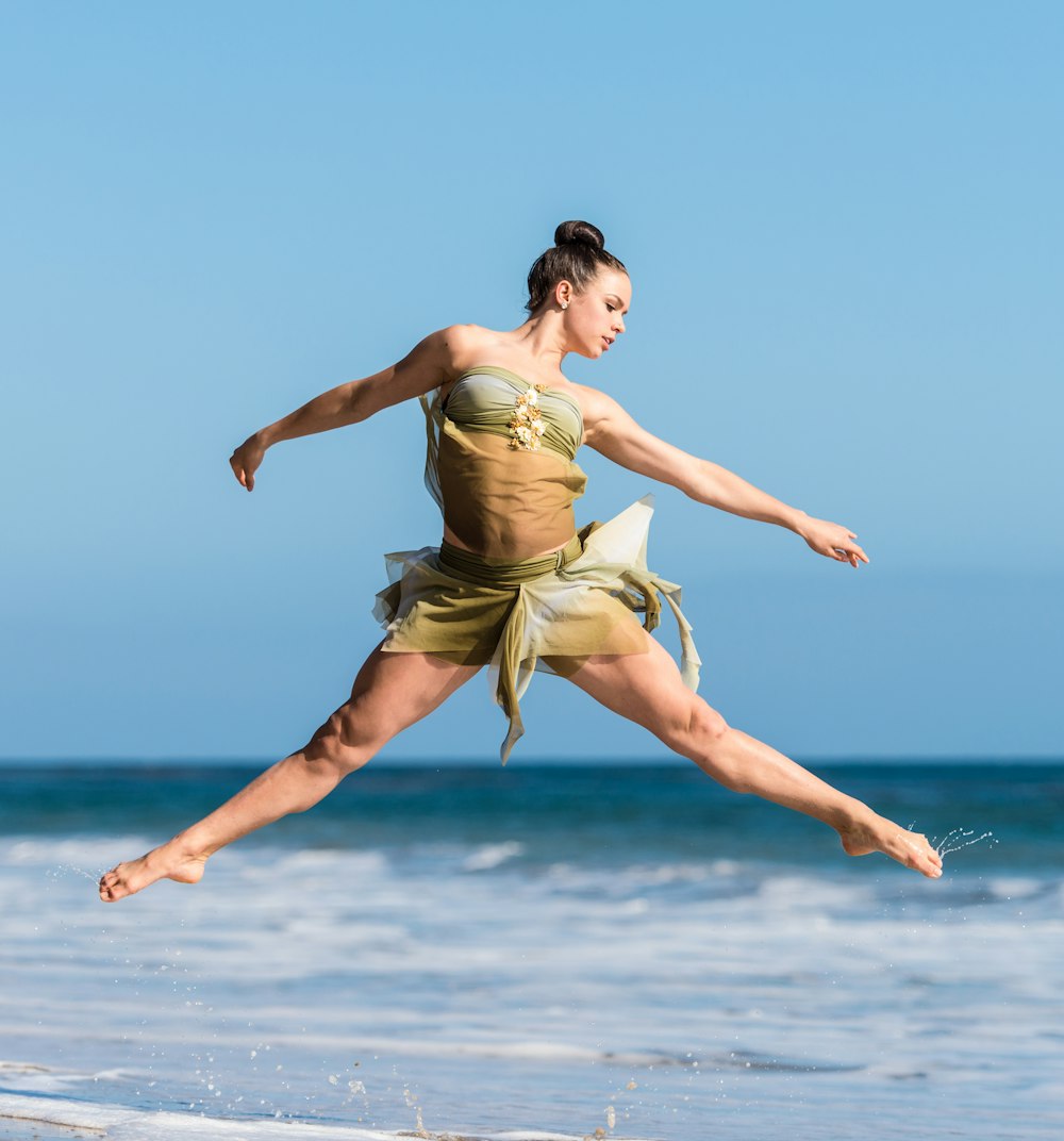 Mujer bailando junto al cuerpo de agua durante el día