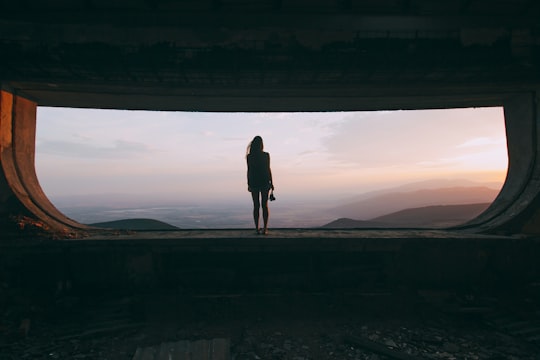 silhouette of woman standing on the edge looking at mountains in Buzludzha Bulgaria