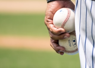 person holding two baseballs