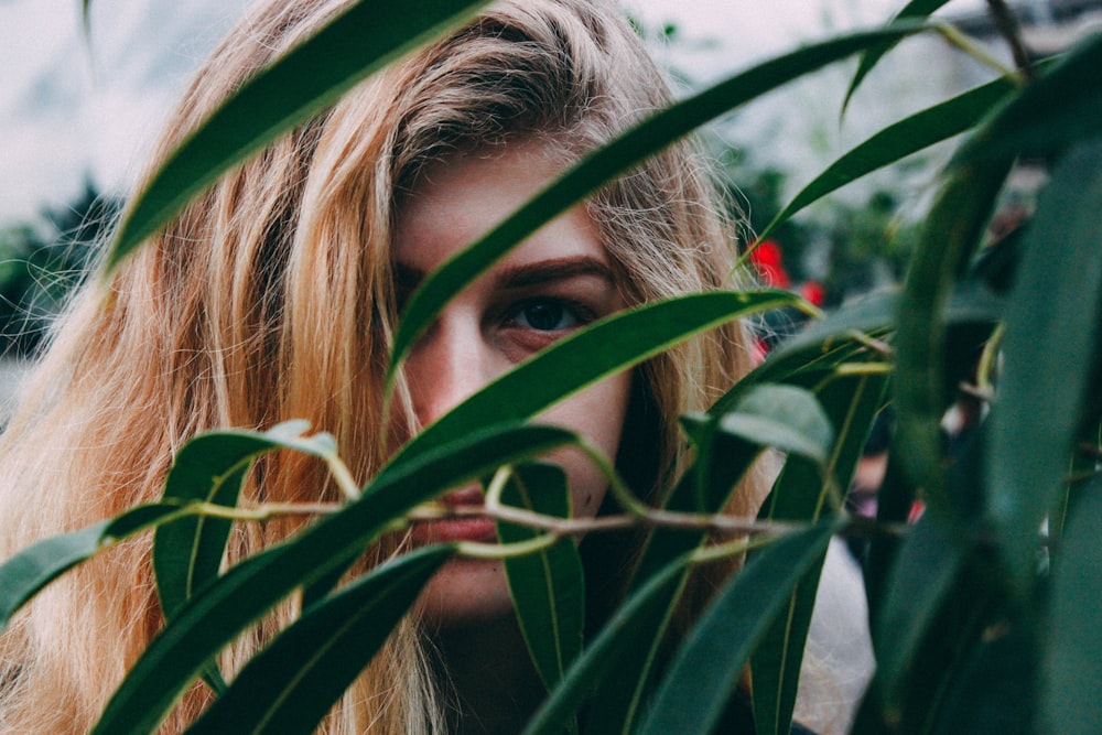 Femme se cachant derrière des plantes