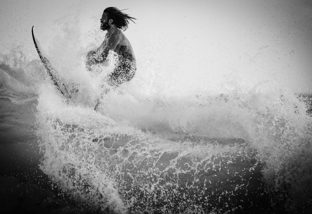 fotografia in scala di grigi dell'uomo che fa surf