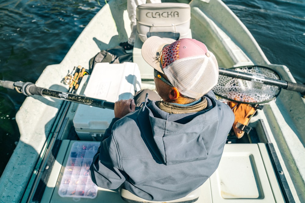 man wearing jacket and cap riding boat